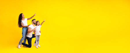 Excited Middle-Eastern Family Pointing Finger Aside Over Yellow Background, Panorama