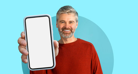 Smiling Man Holds Smartphone in Vibrant Setting, Showcasing Modern Connection and Communicationの写真素材