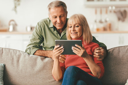 Happy Senior Couple Using Digital Tablet Browsing Internet At Home