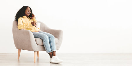 Happy black lady with coffee mug having phone conversation