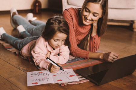 Smiling woman using laptop, girl drawing greeting cardの写真素材