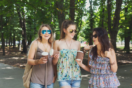 Three beautiful young boho chic stylish girls walking in park.の写真素材