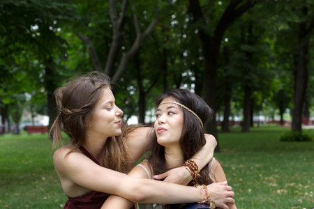 Two happy young girls hug each other in summer parkの写真素材
