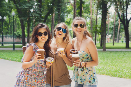 Three beautiful young stylish girls walking in park.