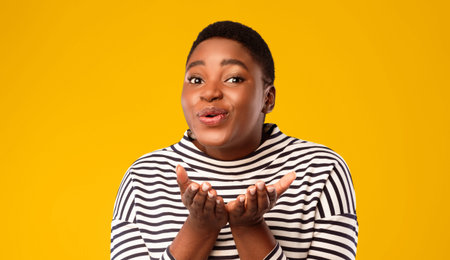 Cheerful Plus-Sized Black Woman Sending Air Kisses Over Blue Backgroundの写真素材