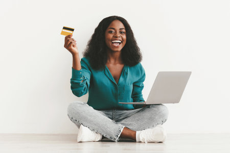 Emotional black woman with laptop and credit cardの写真素材
