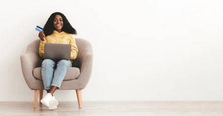 Relaxed black lady making online order, using computerの写真素材