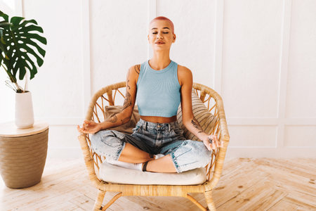 Woman Meditating in a Cozy Chair at Home During a Peaceful Moment of Relaxationの写真素材