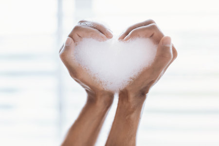 Creating a Heart Shape With Bubbles Using Hands in Bright Indoor Lightの写真素材