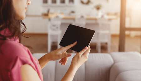 Woman Using Tablet in Cozy Living Room During Afternoon Lightの写真素材
