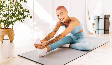 Young Woman Stretching on Yoga Mat in Bright Studio With Natural Light