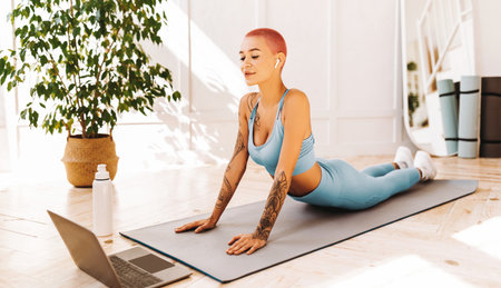 Woman Practicing Yoga at Home With Laptop and Plant in Bright Room