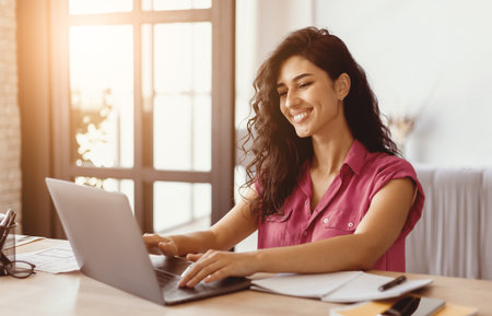 Woman Working on Laptop at Home Office in Bright Daylightの写真素材