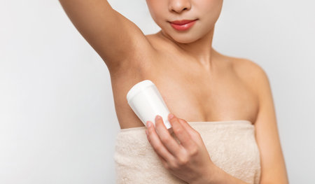 Young Asian woman using applying deodorant in bathroom