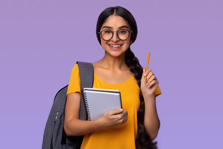 Indian woman holding pen and notebook at purple studio