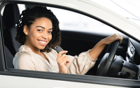 Joyful Woman Showing Key Sitting In Drivers Seat In Automobileの写真素材