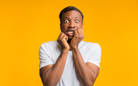 Scared African American Guy Touching Face Posing On Yellow Background