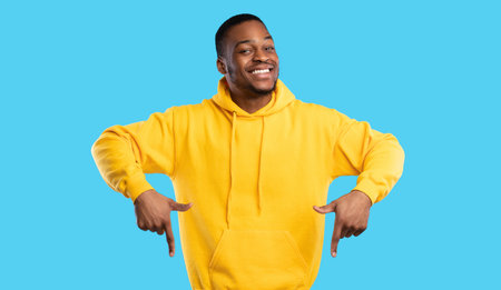 Happy African American Guy Pointing Fingers Down Standing On Blue Backgroundの写真素材