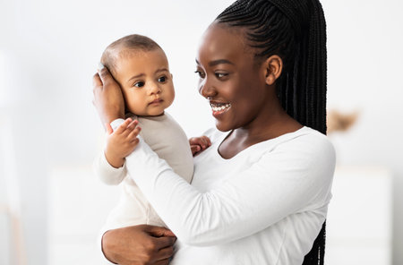 African American mom hugging her cute baby at homeの写真素材