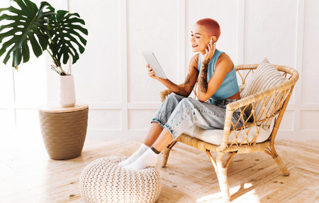 Young Woman Enjoying Leisure Time Reading a Tablet While Relaxing at Homeの写真素材