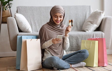 Arab Lady Sitting Among Shopper Bags With Smartphone And Credit Cardの写真素材