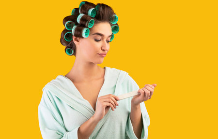 Housewife Doing Manicure With Nail Buffer On Yellow Backgroundの写真素材