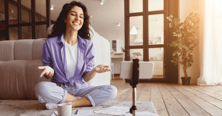 Woman Smiling While Conducting a Video Call in a Bright Living Room Settingの写真素材
