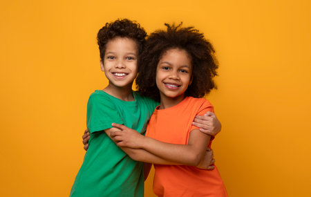 Two Children Hugging in Front of Yellow Backgroundの写真素材