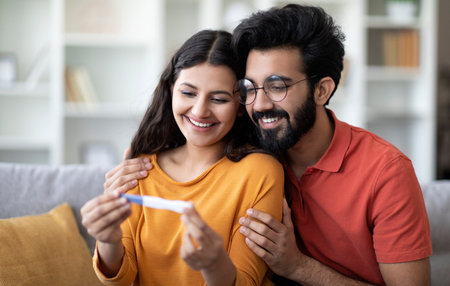 Happy Young Indian Couple Looking At Positive Pregnancy Test At Homeの写真素材