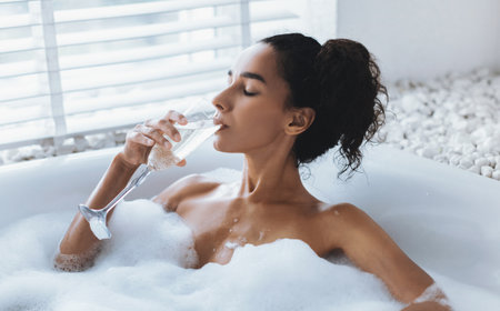 Relaxing in a Spa Bath With Bubbles and a Glass of Sparkling Drinkの写真素材