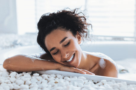 Woman Enjoys a Relaxing Bath Surrounded by Smooth Stones in a Serene Spaceの写真素材