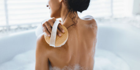 Relaxing Self-Care Routine in a Modern Bathroom With a Woman Using a Body Brushの写真素材