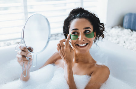 Woman Enjoying a Relaxing Bath While Applying Green Eye Patches for Skincareの写真素材