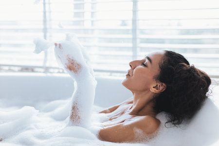 Relaxing Woman Enjoys Bubble Bath in Bright Bathroom During Tranquil Afternoon