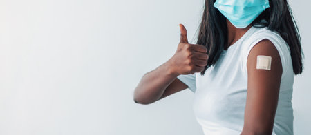 Lady In Mask Showing Shoulder With Patch And Thumbs Upの写真素材