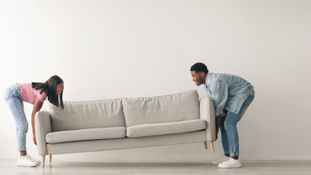 Happy black couple replacing furniture in their new apartmentの写真素材