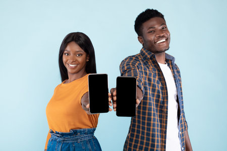 Cheerful Couple Presenting Empty Smartphone Screens for Mockup in Blue Studio Setting