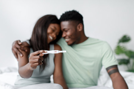 Couple Celebrates Positive Pregnancy Test in Cozy Bedroom During Bright Morning Lightの写真素材