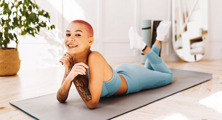 Young Woman With Pink Hair Enjoys Fitness Routine at Home in Cozy Environmentの写真素材