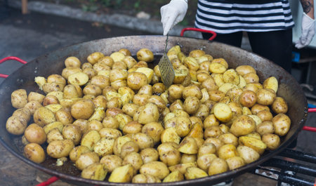 Street fast food festival, roasted potatoes cooked in metal cauldron potの写真素材