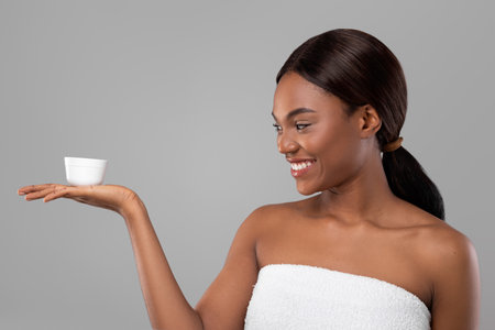 Woman Smiling While Holding a Small Container in a Bright Setting With Gray Backgroundの写真素材
