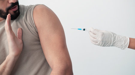 Man Hesitates While Receiving a Vaccination in a Medical Settingの写真素材