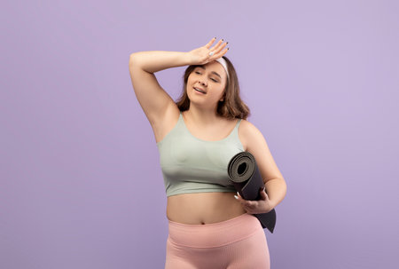 Tired Young European Plus Size Woman in Sportswear Wipes Sweat After Workout Sessionの写真素材