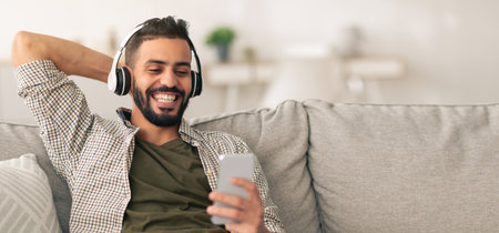 Man Enjoys Music While Relaxing on a Couch in a Cozy Living Roomの写真素材