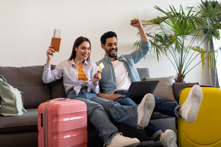 Excited Couple Enjoys Vacation Planning While Relaxing on the Couch Surrounded by Colorful Luggage