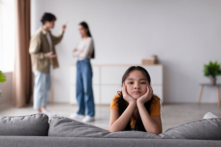 Child Appears Thoughtful While Parents Argue in a Modern Living Room During an Afternoonの写真素材