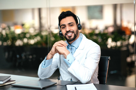 Medical Professional in a White Coat Using a Headset While Providing Patient Support in a Modern Healthcare Office Settingの写真素材