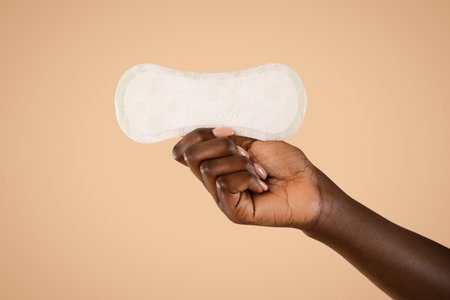 Closeup View of Black Womans Hand Holding Daily Pad Against Beige Backgroundの写真素材