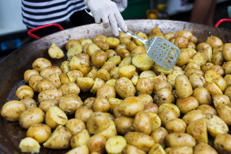 Street fast food festival, roasted potatoes cooked in metal cauldron potの写真素材