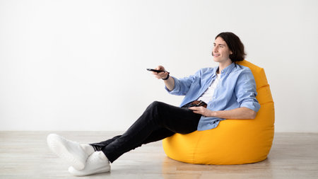 Man Relaxes on a Yellow Bean Bag While Watching Television in a Bright Room